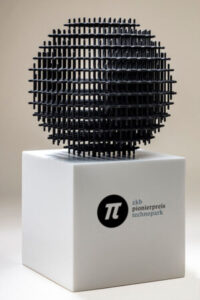 Trophäe des ZKB Pionierpreis Technopark: schwarze, kugelförmige Skulptur auf weissem Sockel mit ZKB-Pionierpreis-Logo.